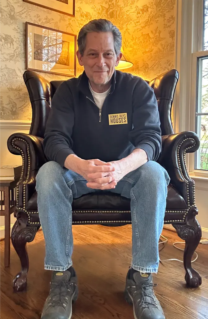 Dennis-Buys-Houses-–-Local-Detroit-Home-Buyer-You-Can-Trust-1 Dennis sitting in a chair in his living room